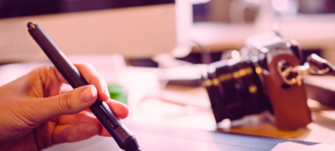 Bureau d'un graphiste : présence d'un ordinateur et d'un appareil photo